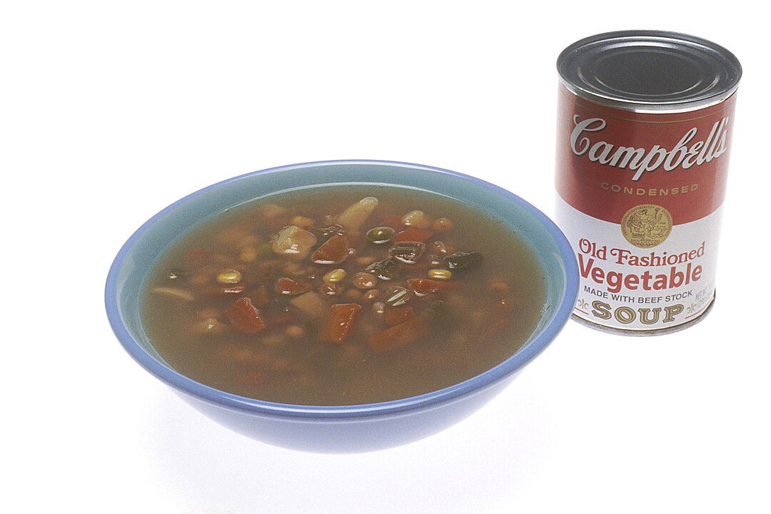 Bowl of vegetable soup beside a can of Campbell's Old-Fashioned Vegetable Soup