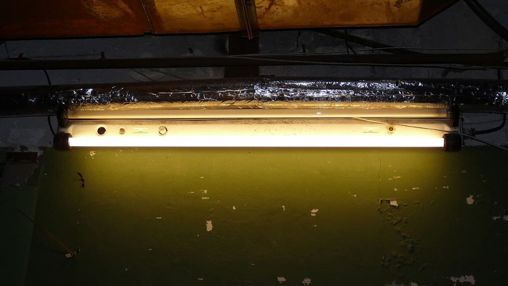 old basement lighting, neglected industrial space, temporary repair setup, outdated workshop environment, maintenance issue in storage room, prepping area for renovation