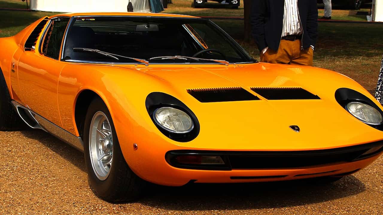 1971 Lamborghini Miura P400 SV, vibrant yellow paint, sleek aerodynamic body, pop-up headlights, black rear louvers, flared rear fenders, mid-engine layout, parked on a clean road surface