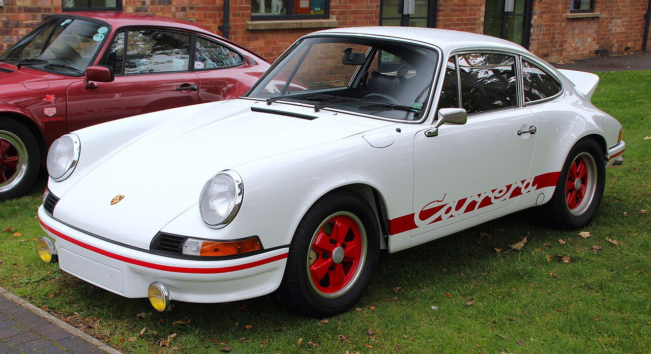 1973 Porsche 911 Carrera RS, classic sports car, white body with red Carrera script, ducktail rear spoiler, round headlights, flared wheel arches, lightweight design, iconic rear-engine layout