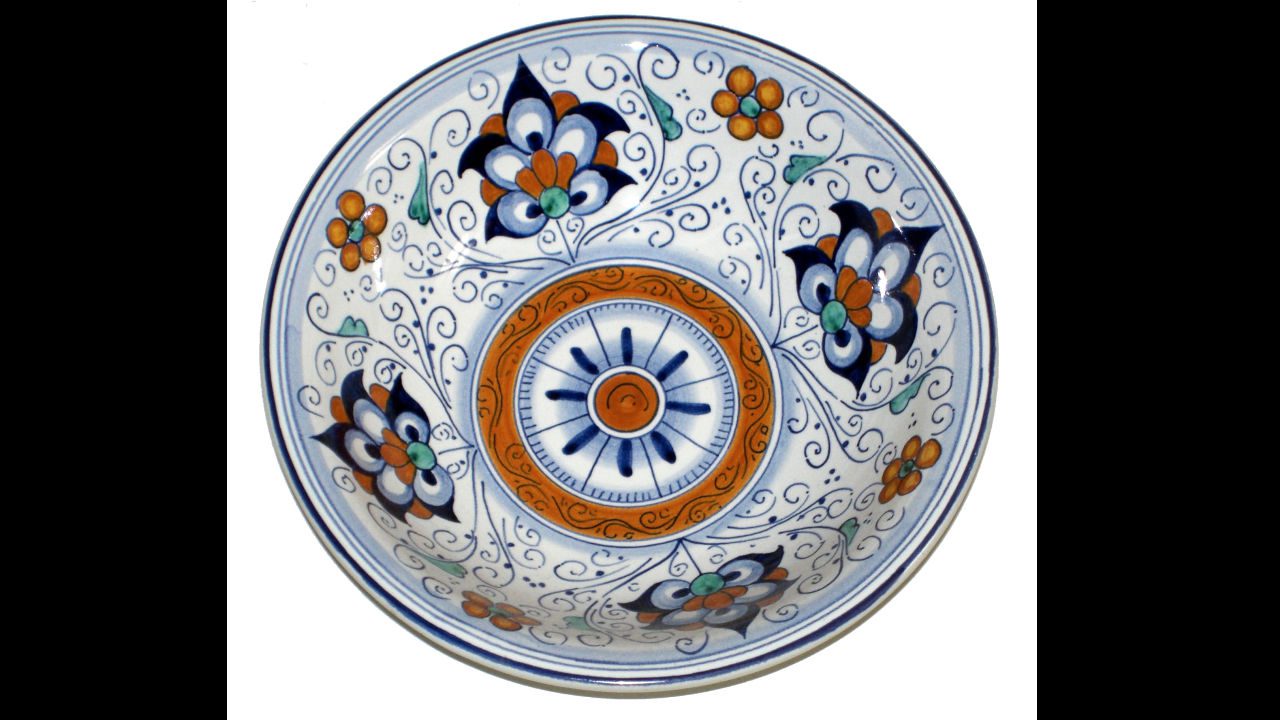 ornate ceramic bowl with floral and geometric patterns in blue, orange, green, and white, featuring a circular medallion in the center and symmetrical flower motifs