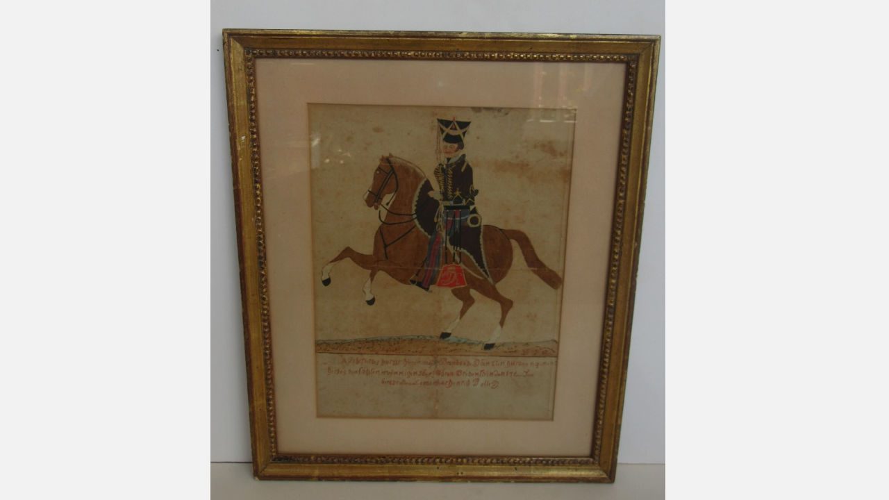 framed 18th-century German folk art painting of a man in traditional military uniform riding a brown horse with handwritten script beneath the image