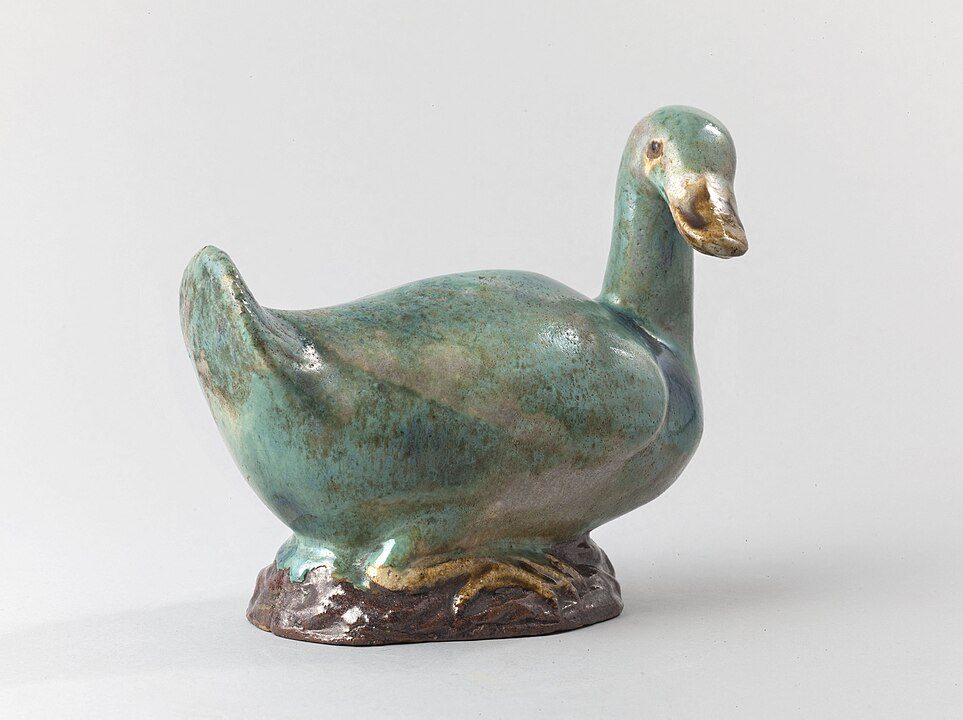 Ceramic duck sculpture, glossy green finish, gold accents on beak and feet, standing on a brown base, white background