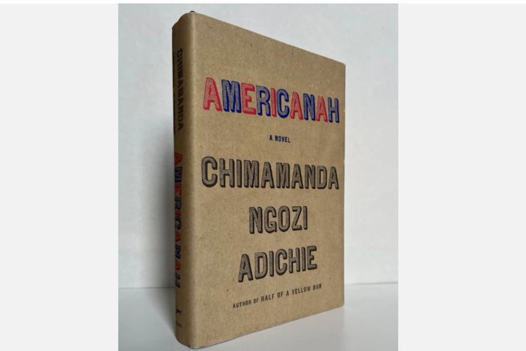 Americanah by Chimamanda Ngozi Adichie, paperback edition, cream-colored cover, bold navy blue title text, red hand-drawn lines across the background, author’s name in uppercase, published by Anchor Books