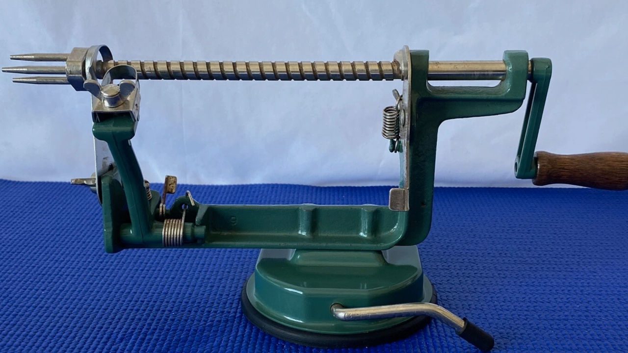  Antique green metal apple peeler and corer with wooden handle, suction base, and exposed gears