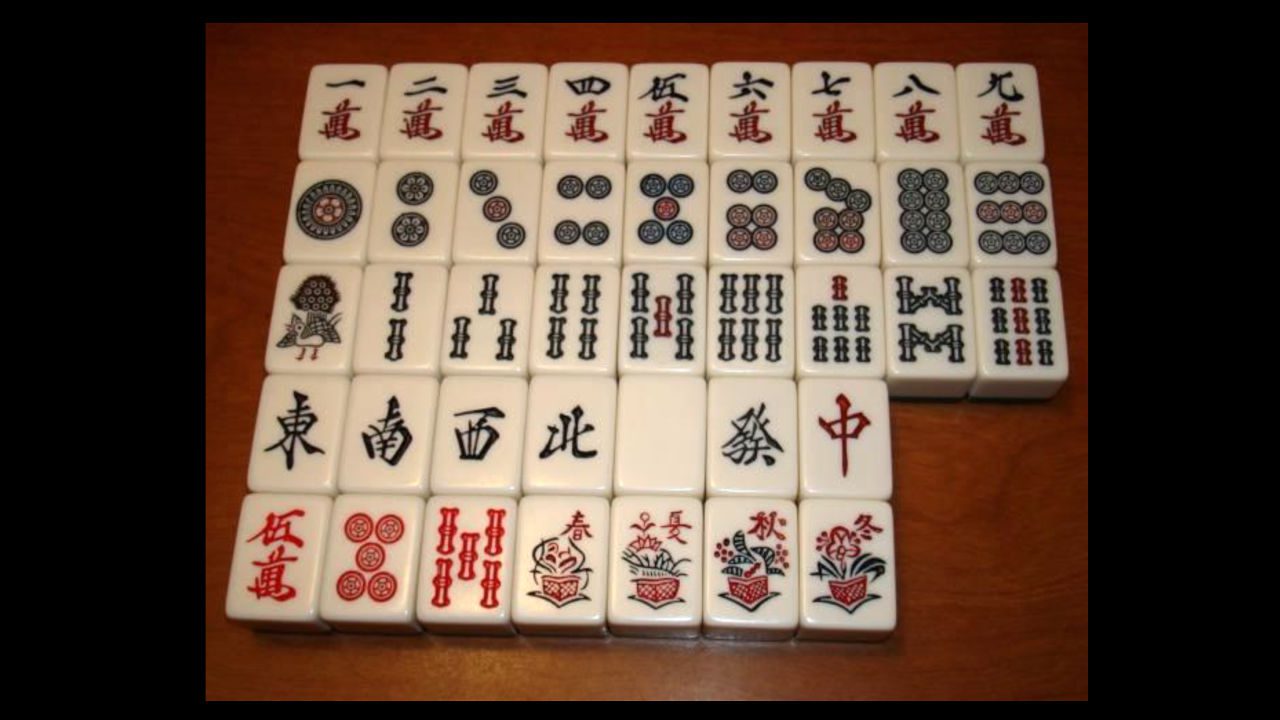 antique Mahjong tile set arranged in rows, featuring dots, bamboo, characters, winds, dragons, flowers, and seasons on white tiles with red, black, and green designs