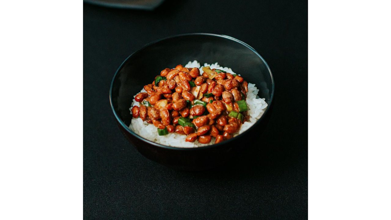 Bowl of white rice topped with seasoned beans and chopped green onions