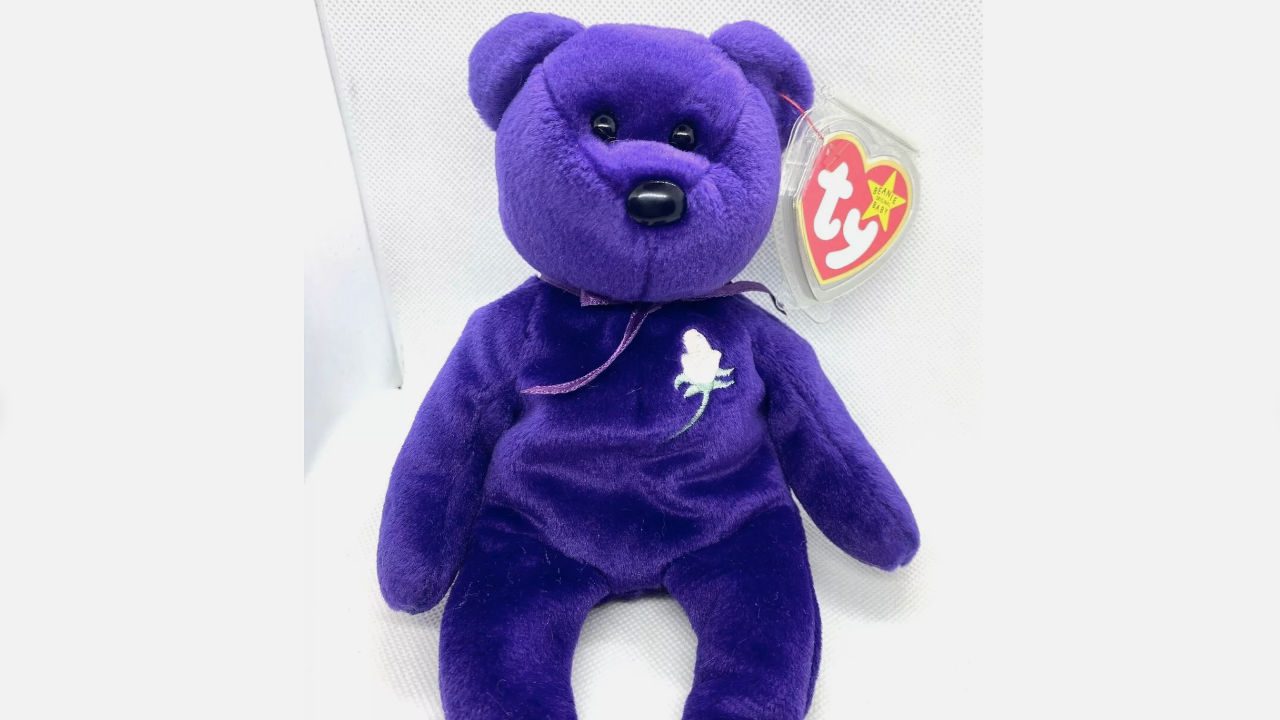  Purple plush TY Beanie Baby bear, white rose on chest, plastic heart tag, sitting upright, white background