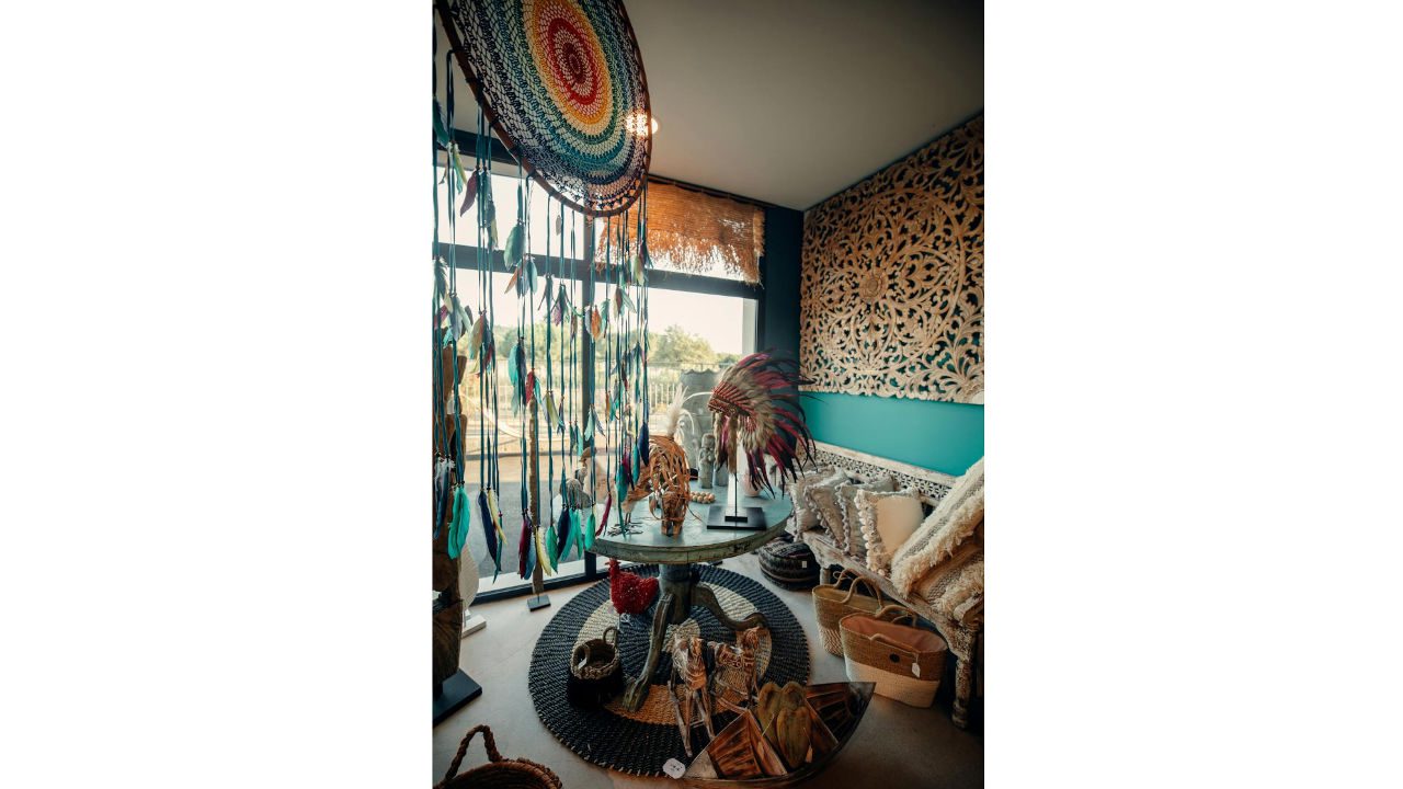 Colorful bohemian room with eclectic decor, feather wall hangings, patterned furniture, and tribal artifacts
