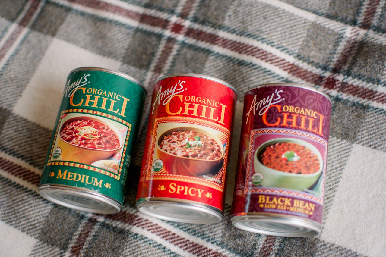 Three cans of Amy’s Organic Chili—Medium, Spicy, and Black Bean—placed on a plaid blanket