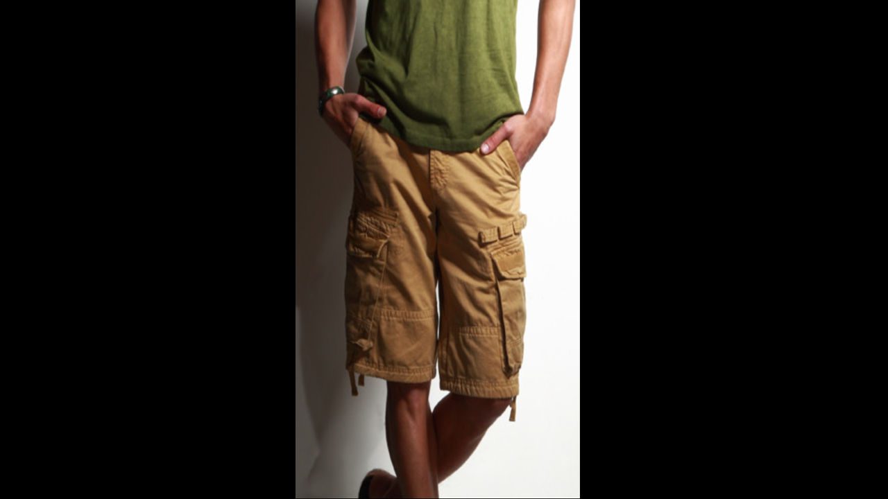 Person wearing tan cargo shorts with multiple side pockets, standing casually with hands in pockets