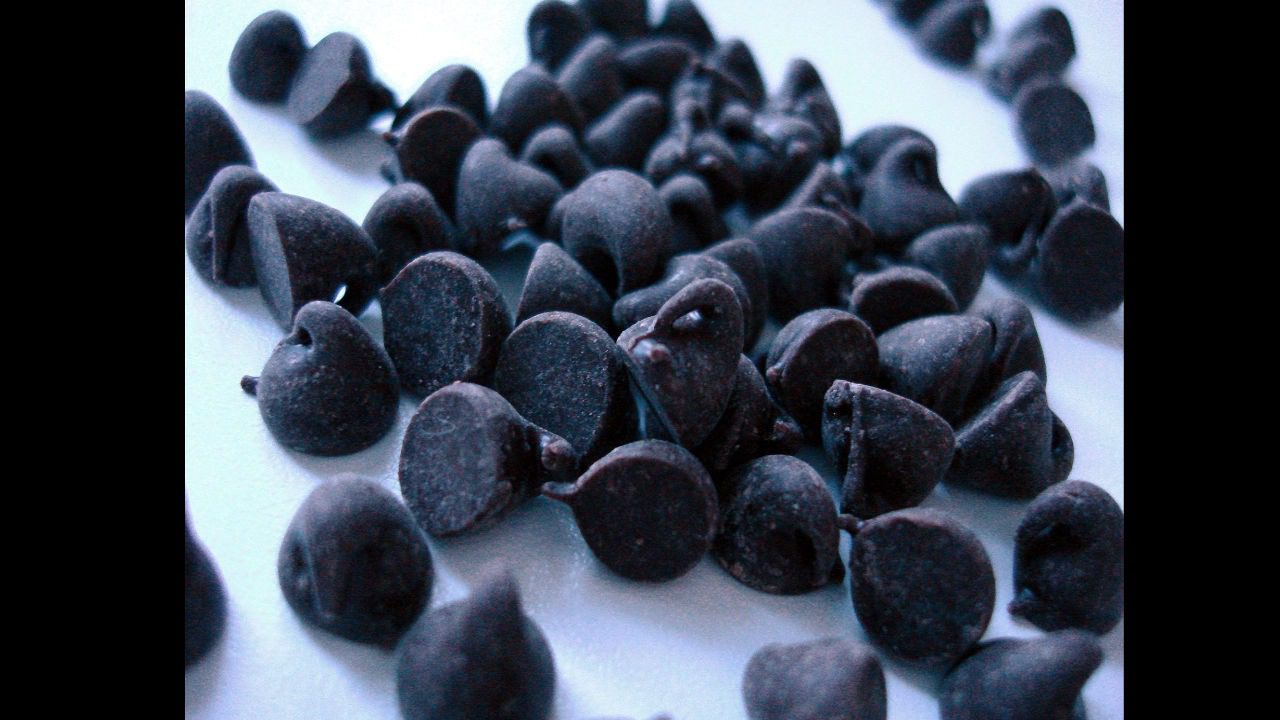 Scattered dark chocolate chips on a smooth white surface