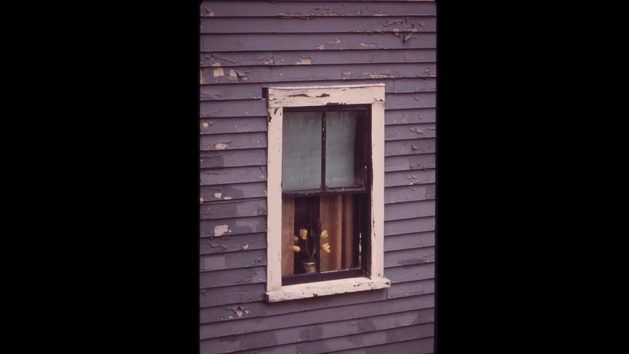 Close-up of a house window with cracked and peeling exterior paint