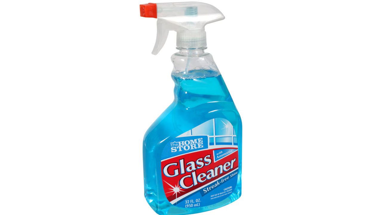 Spray bottle of The Home Store Glass Cleaner with blue liquid, red label, and red trigger nozzle