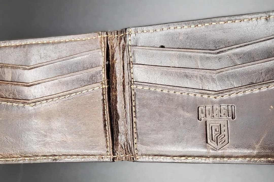 Fossil leather wallet, brown leather, multiple card slots, stitching detail, embossed Fossil logo, worn texture, vintage look