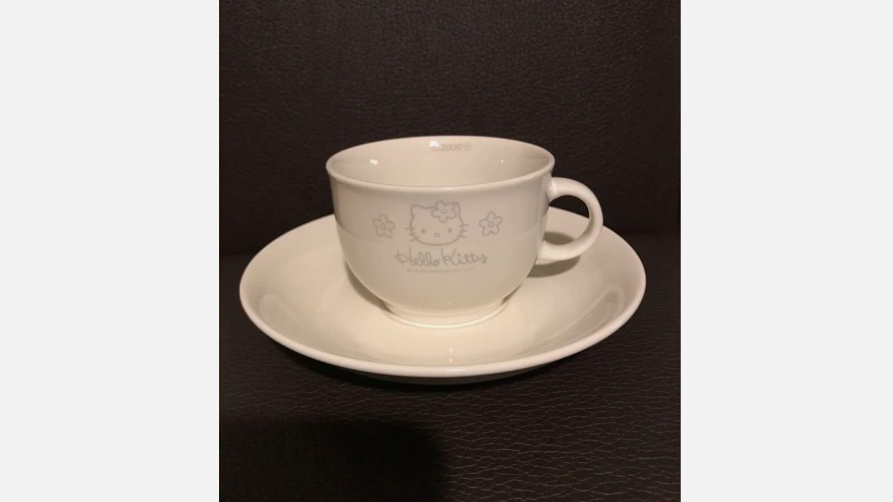  White ceramic Hello Kitty cup and saucer with subtle gray floral and character design, dated 2000