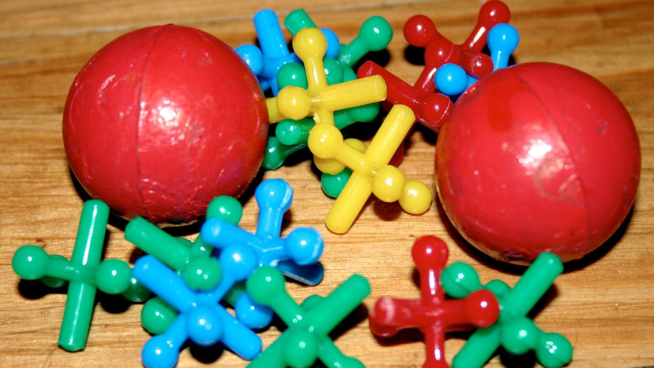 Colorful jacks game set with red rubber balls on a wooden surface