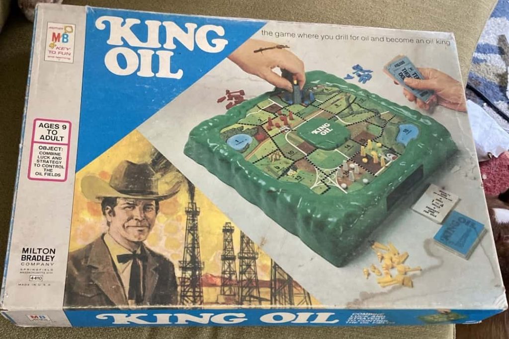 King Oil board game box, featuring a raised plastic game board with grid sections, oil derricks, game money, cards, and artwork of a cowboy with oil rigs in the background