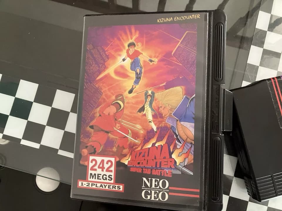 Kizuna Encounter Neo Geo cartridge, original SNK game label, black plastic casing, Neo Geo branding, placed on a flat surface, retro fighting game collectible