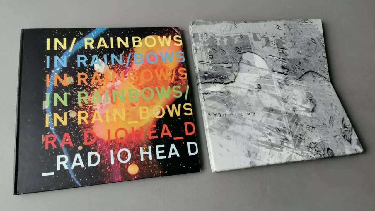Radiohead’s "In Rainbows" and "Kid A" deluxe vinyl editions, side by side on a gray surface, bold colorful cover, grayscale abstract cover, limited edition packaging