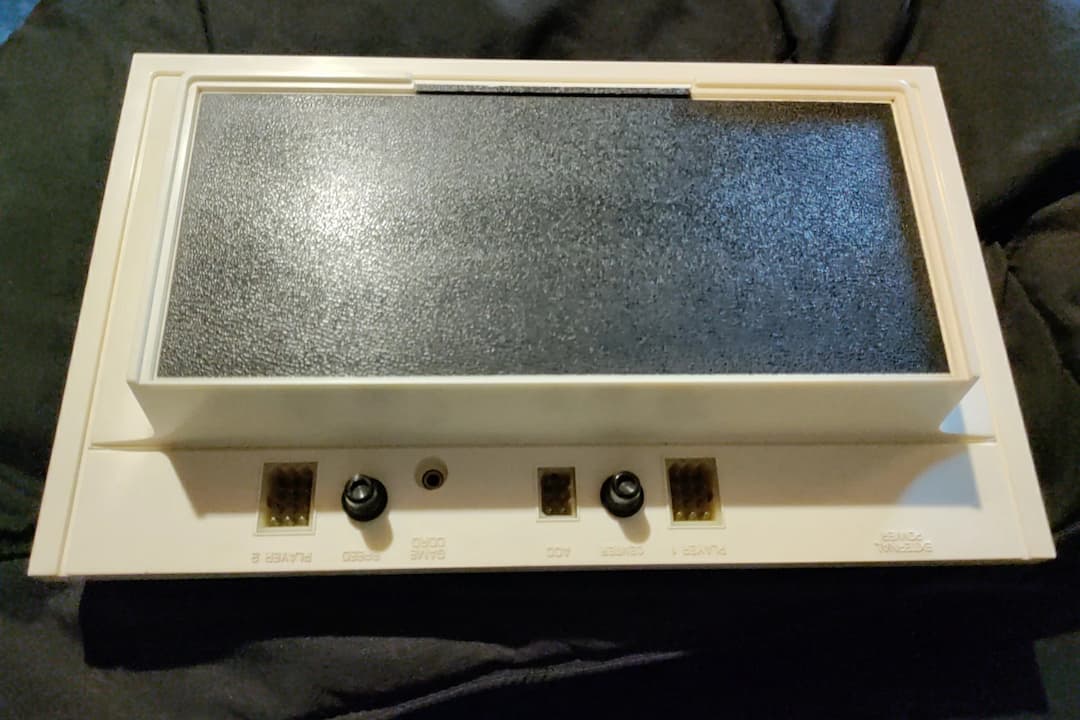 Magnavox Odyssey console, rectangular white plastic casing, black front panel with dials, paired with two wired controllers, early home video game system, 1970s design
