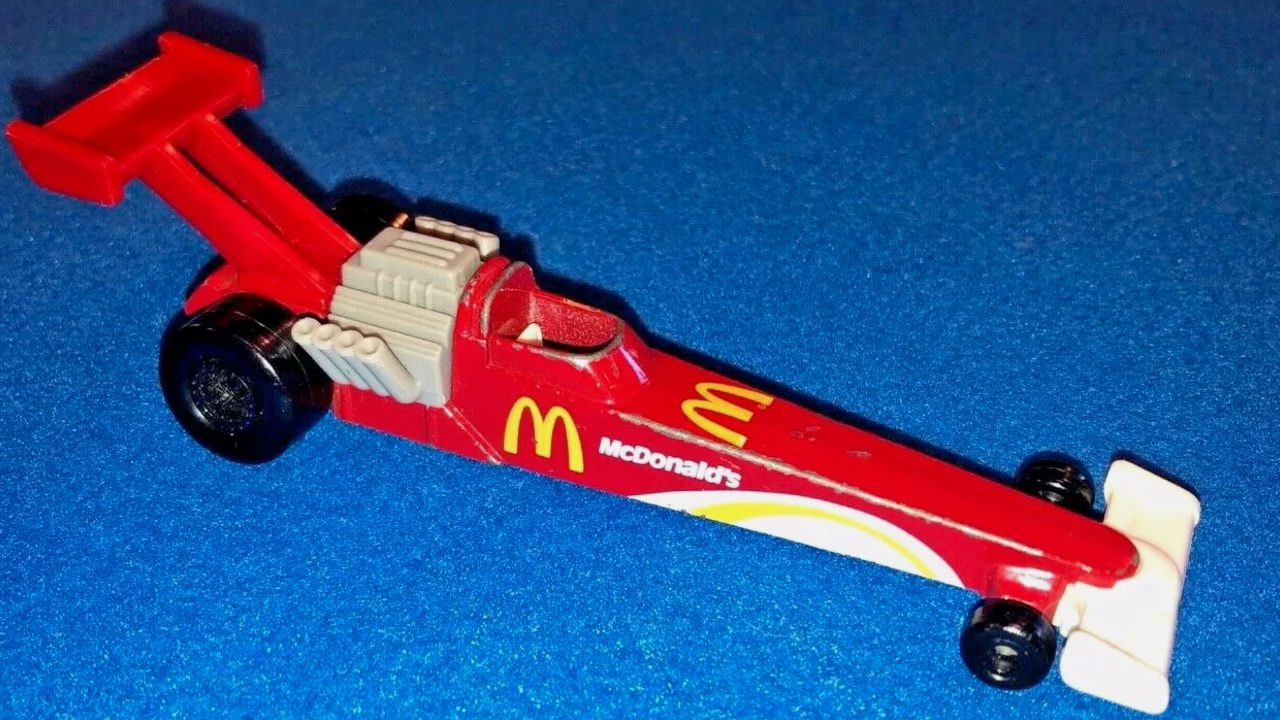 McDonald's red toy dragster car with yellow arches and engine detail on a blue background