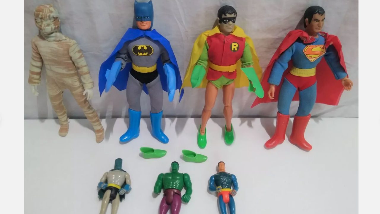 vintage Mego action figures including Mummy, Batman, Robin, Superman, plus three smaller superhero figures, displayed on white surface