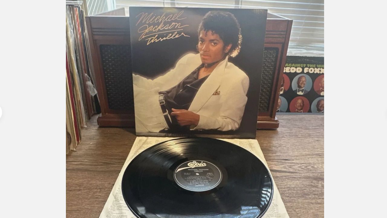 Michael Jackson’s “Thriller” vinyl record with original album cover displayed on a wooden table near a record player