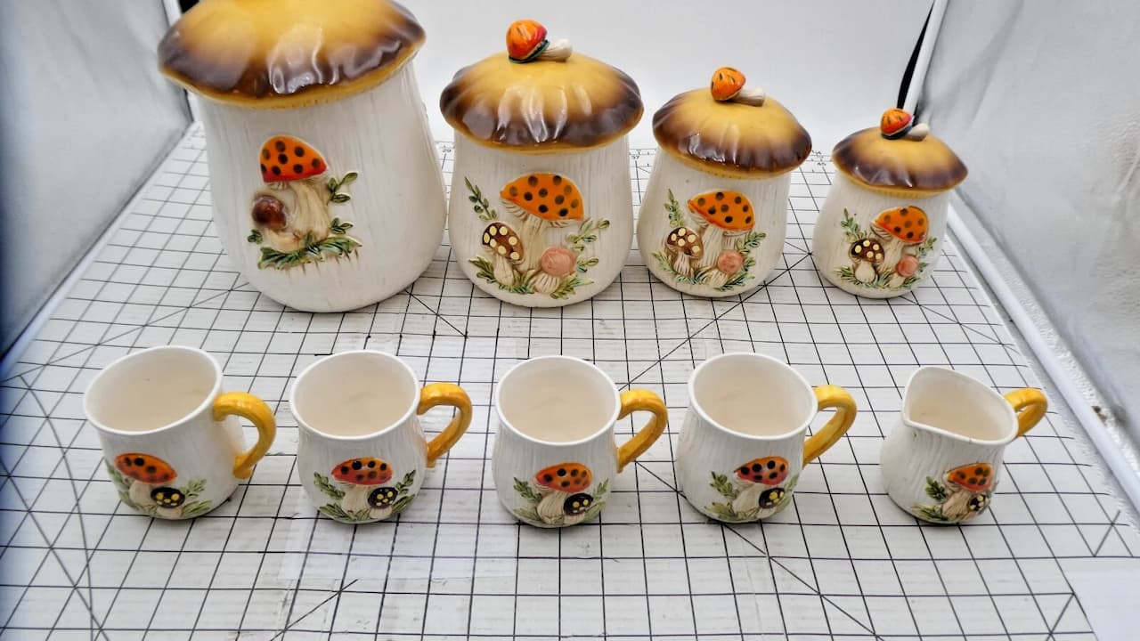 Mushroom motif kitchenware, ceramic canisters with mushroom illustrations, warm earthy tones, matching lids with handles, vintage 1970s style, decorative kitchen set