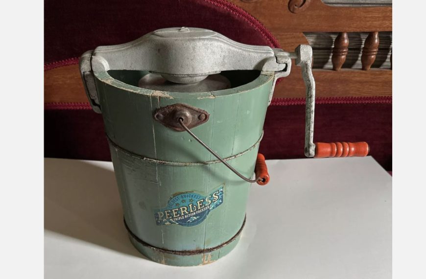 Vintage Peerless hand-crank ice cream maker with green wooden bucket and metal crank handle on table