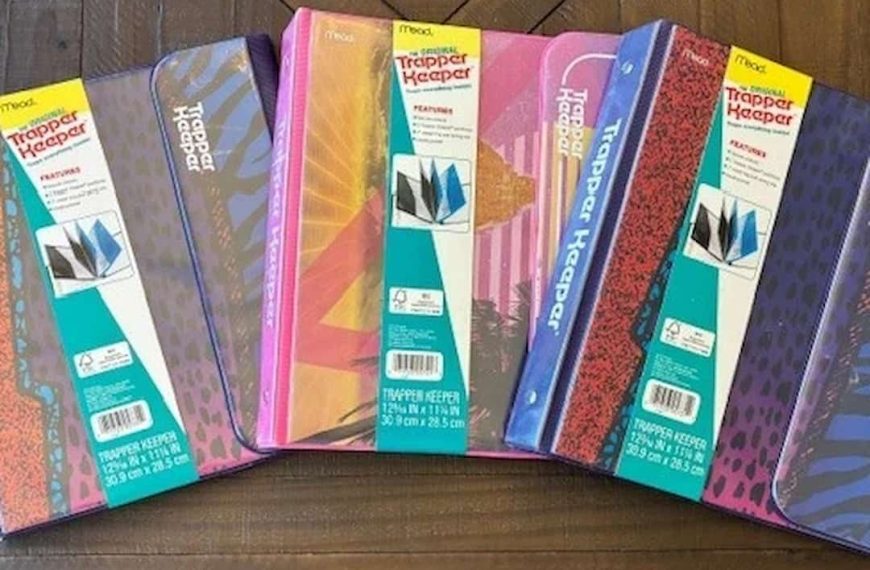 old Trapper Keeper notebooks, colorful covers, Velcro flap closure, worn edges, retro designs, plastic binder rings, stacked on desk