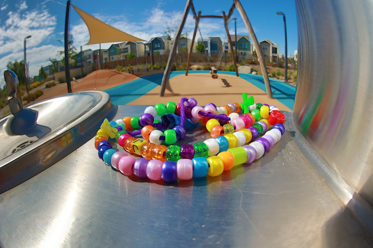 Colorful plastic bead bracelets on a metal surface near a playground swing set