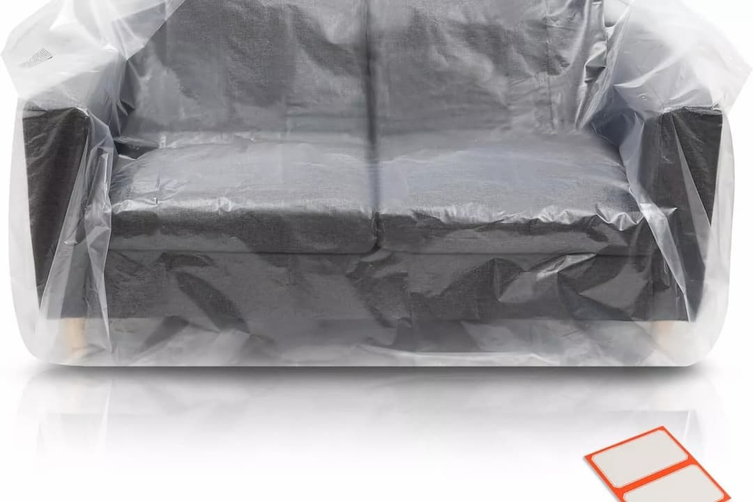 plastic furniture covers, transparent material, snug fit over sofa, protective layer, wrinkle lines visible, living room setting