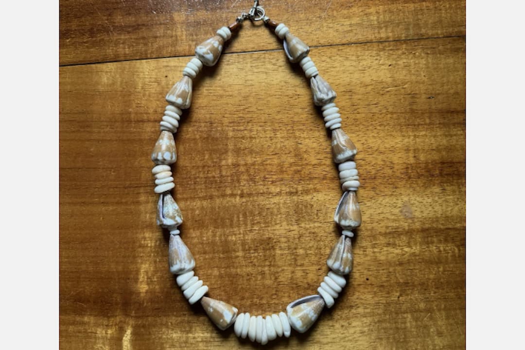 Puka shell necklaces, small white shell beads, rounded and polished, strung closely together, natural beach style, often with clasp closure, laid flat or worn around the neck