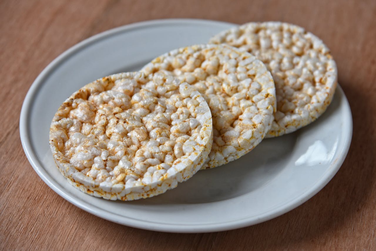 Three round rice cakes stacked on a white ceramic plate on a wooden table