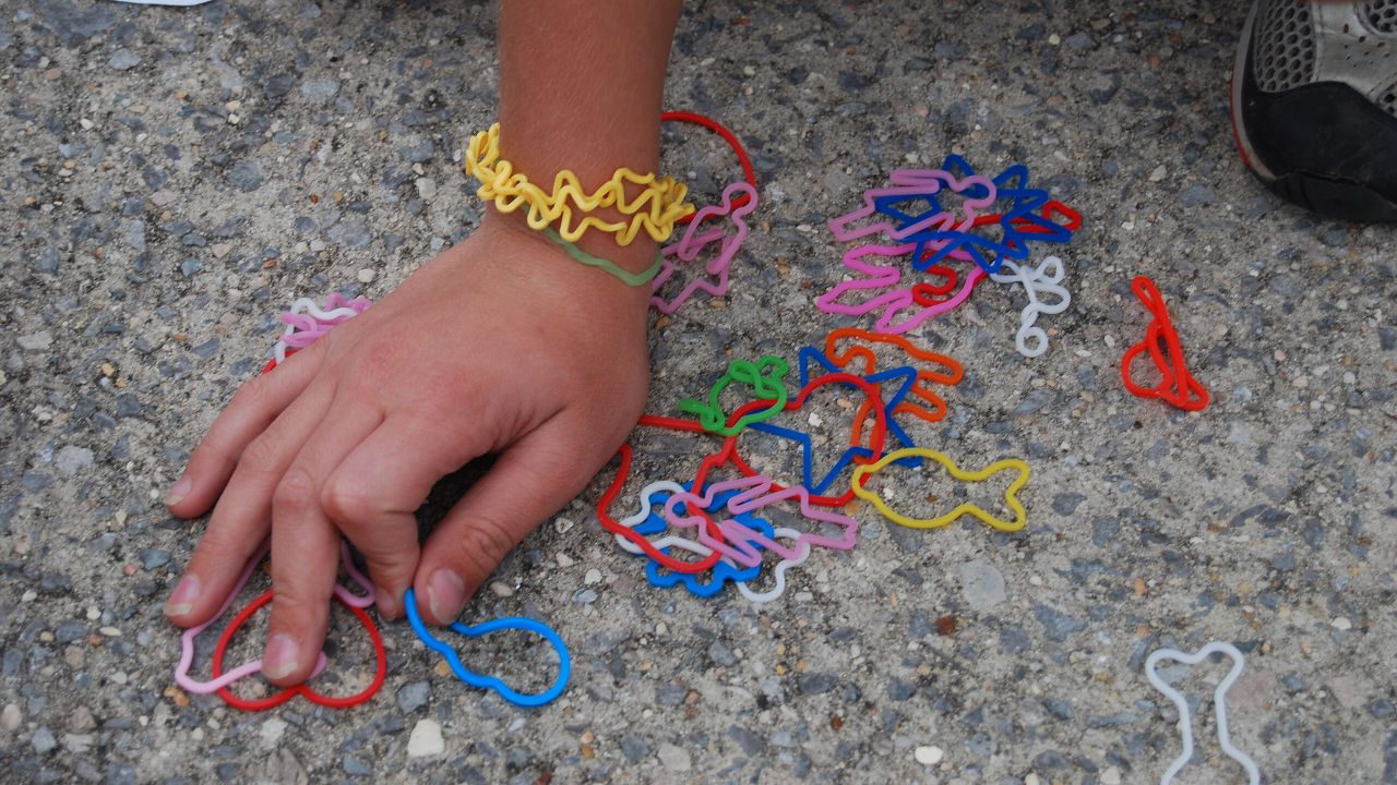 Child’s hand on pavement with colorful Silly Bandz shaped like animals and objects