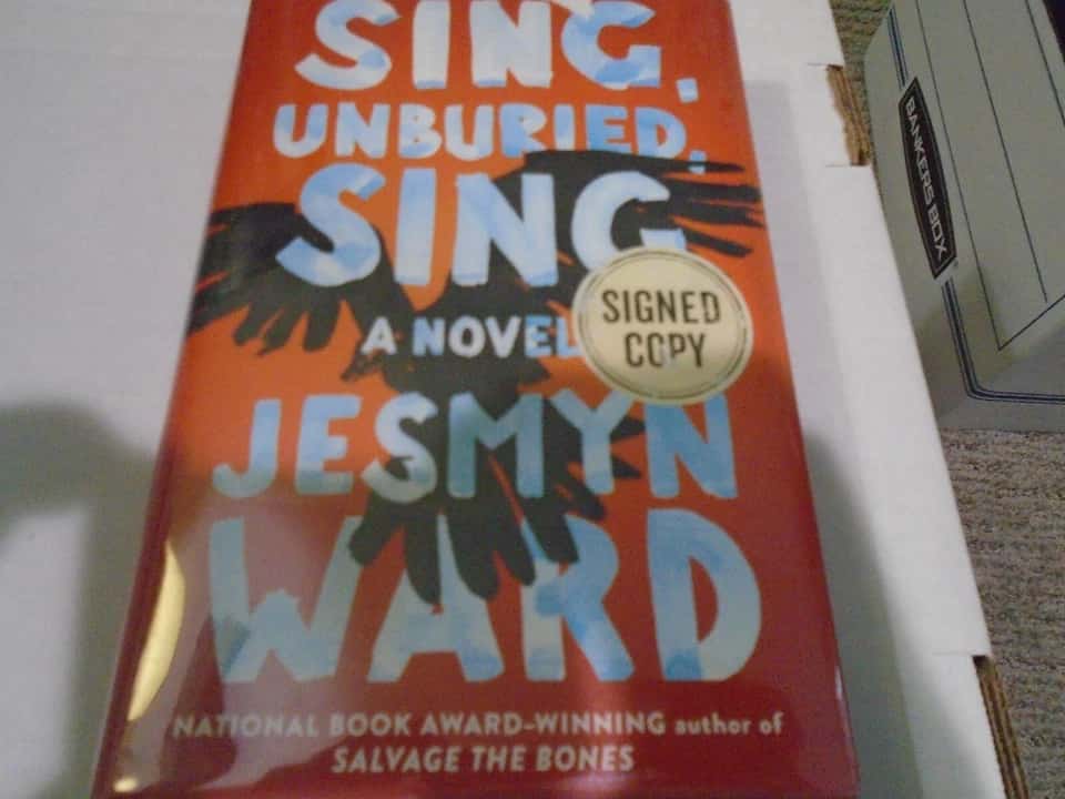 Sing, Unburied, Sing by Jesmyn Ward, paperback edition, bold red and black cover design, large white title text, silhouette of a bird in flight, National Book Award sticker visible, published by Scribner