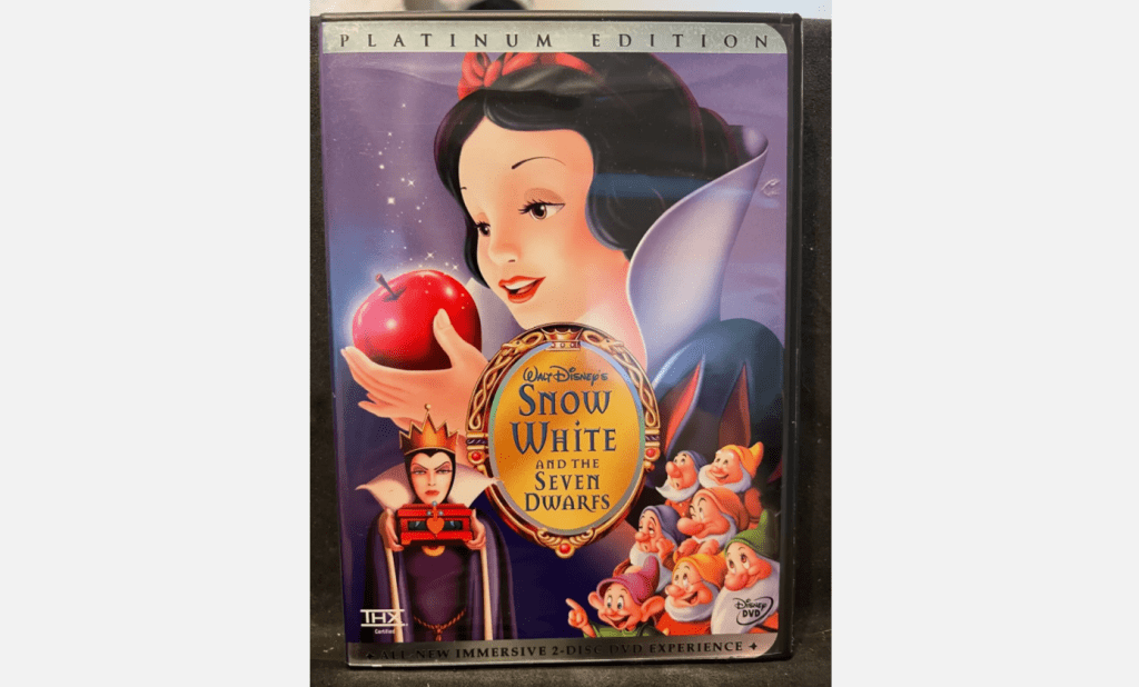 Snow White holding a red apple, VHS cover of Disney’s “Snow White and the Seven Dwarfs”, large gold sticker on the front, dwarfs gathered at the bottom, purple background, vintage Black Diamond Edition design