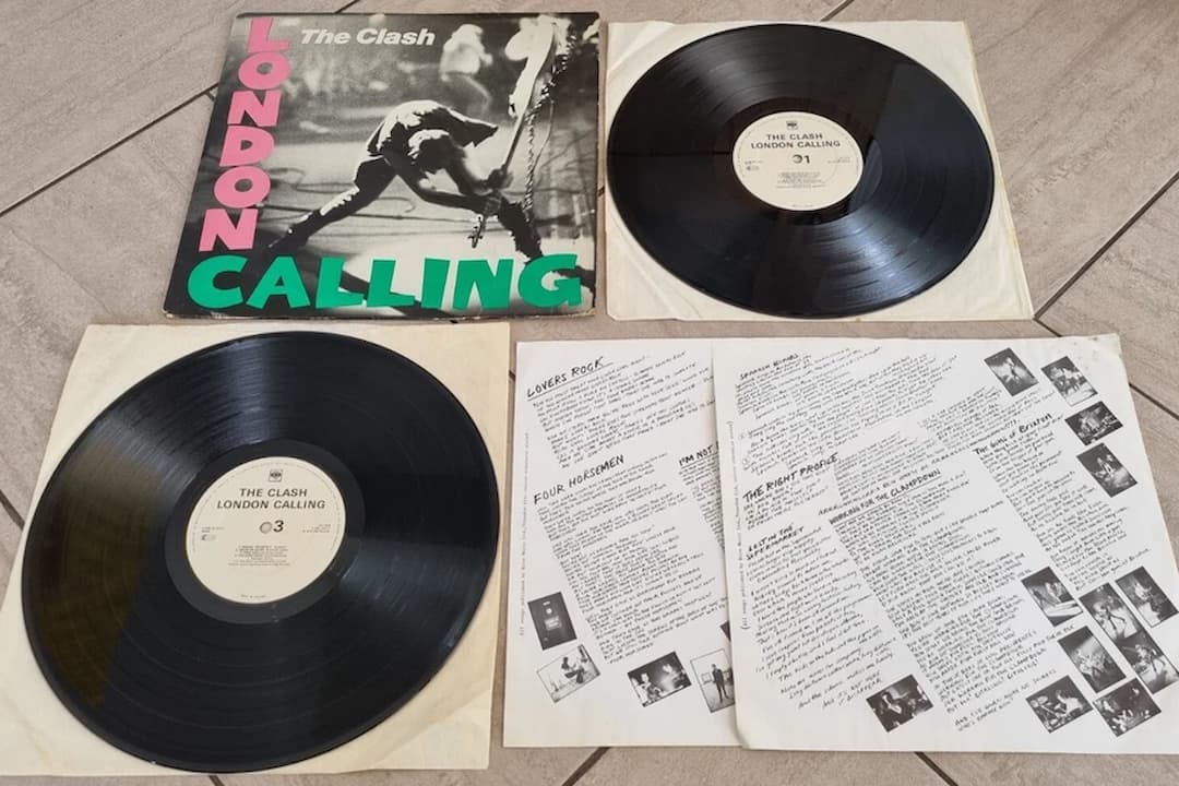 The Clash – London Calling album cover, black-and-white photo of Paul Simonon smashing his bass guitar, pink and green bold text, punk rock energy, inspired by Elvis Presley’s debut album design