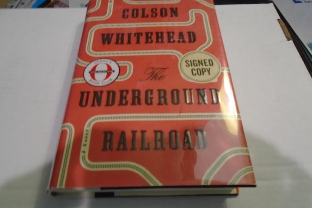 The Underground Railroad by Colson Whitehead, hardcover edition, bright red cover, white title text in bold serif font, black railroad track illustration winding across, National Book Award and Pulitzer Prize stickers, published by Doubleday