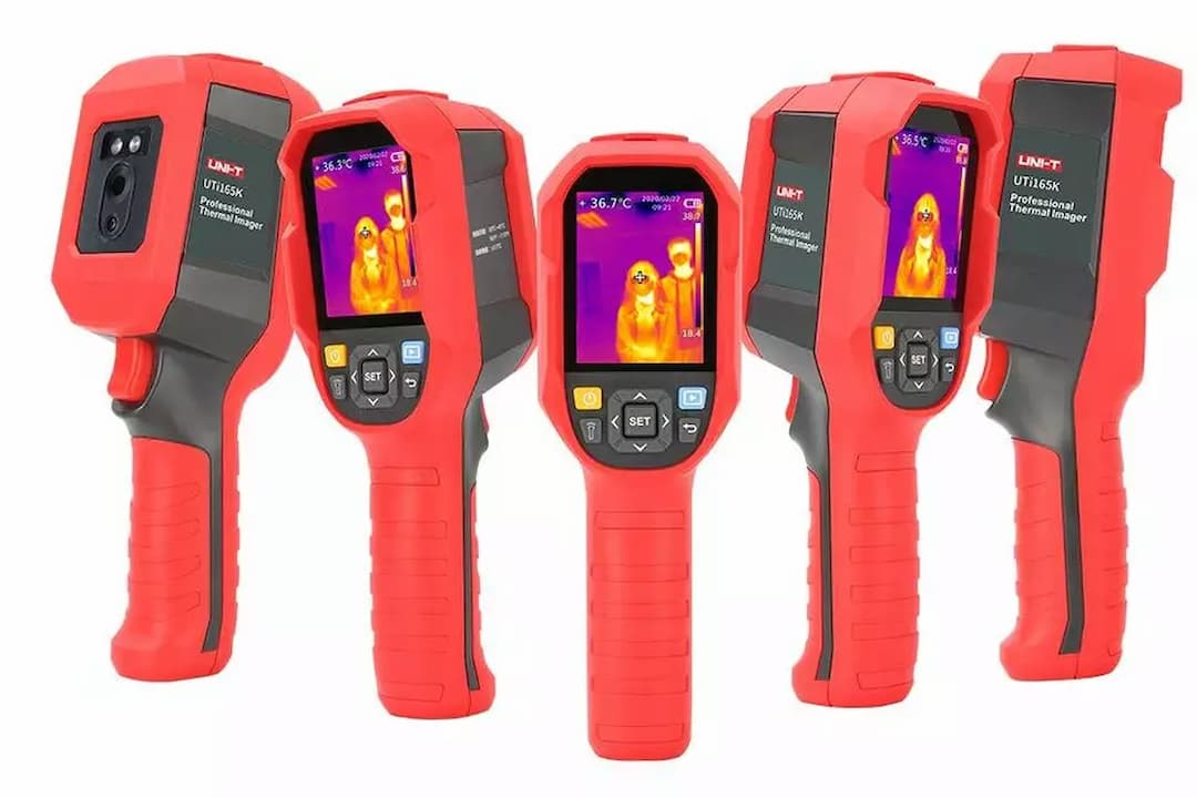 Thermal scanning camera, rectangular body, mounted on a tripod, front-facing dual lenses, visible heat sensor, small display screen on side, matte black finish, set indoors against a neutral background