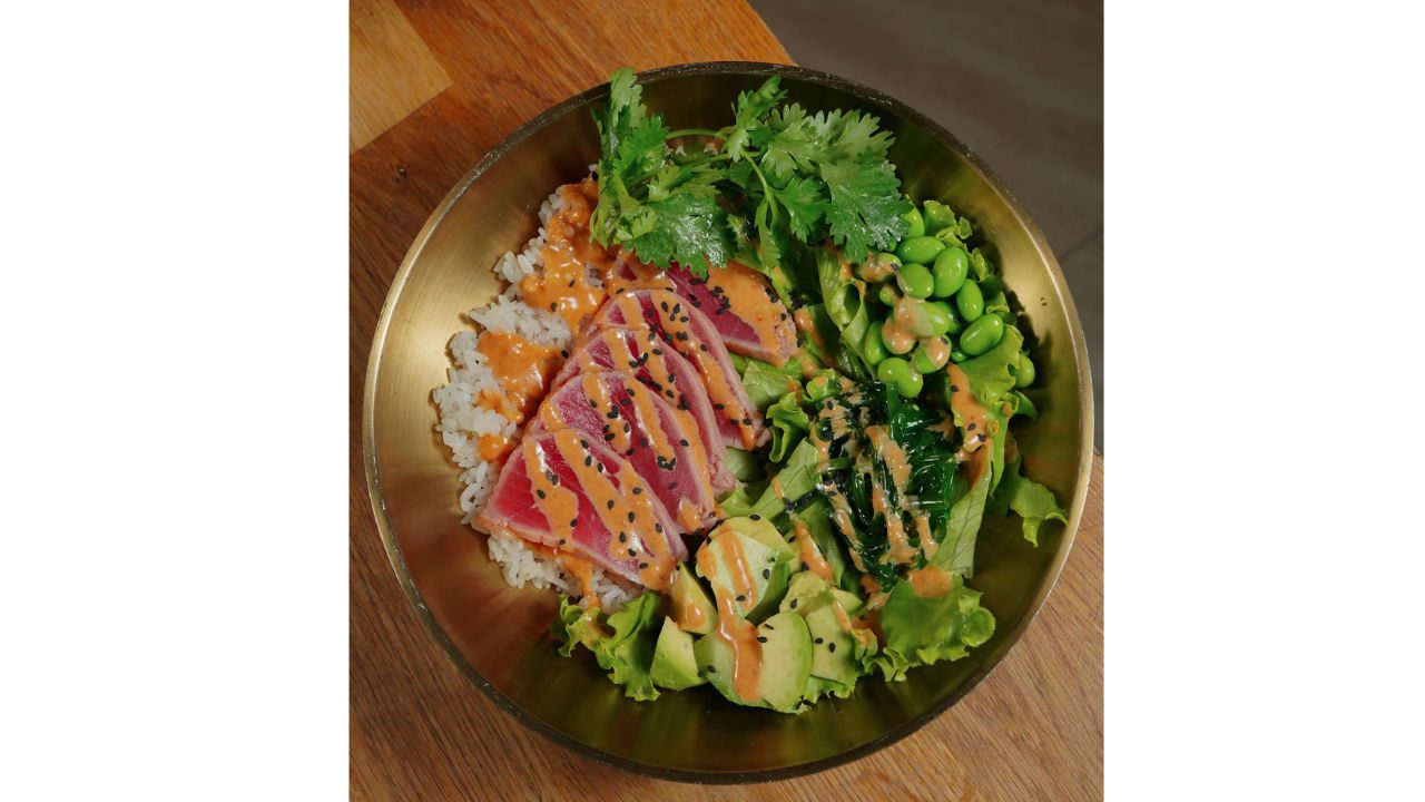 Tuna rice bowl with sliced seared tuna, avocado, edamame, seaweed, and rice, topped with spicy mayo