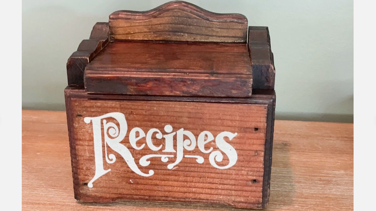 Vintage wooden recipe box with the word "Recipes" written in white decorative script on the front