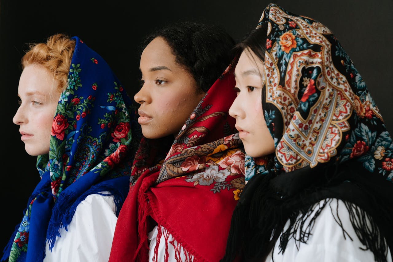 three women in profile wearing vibrant vintage scarves in blue, red, and black with floral and paisley patterns
