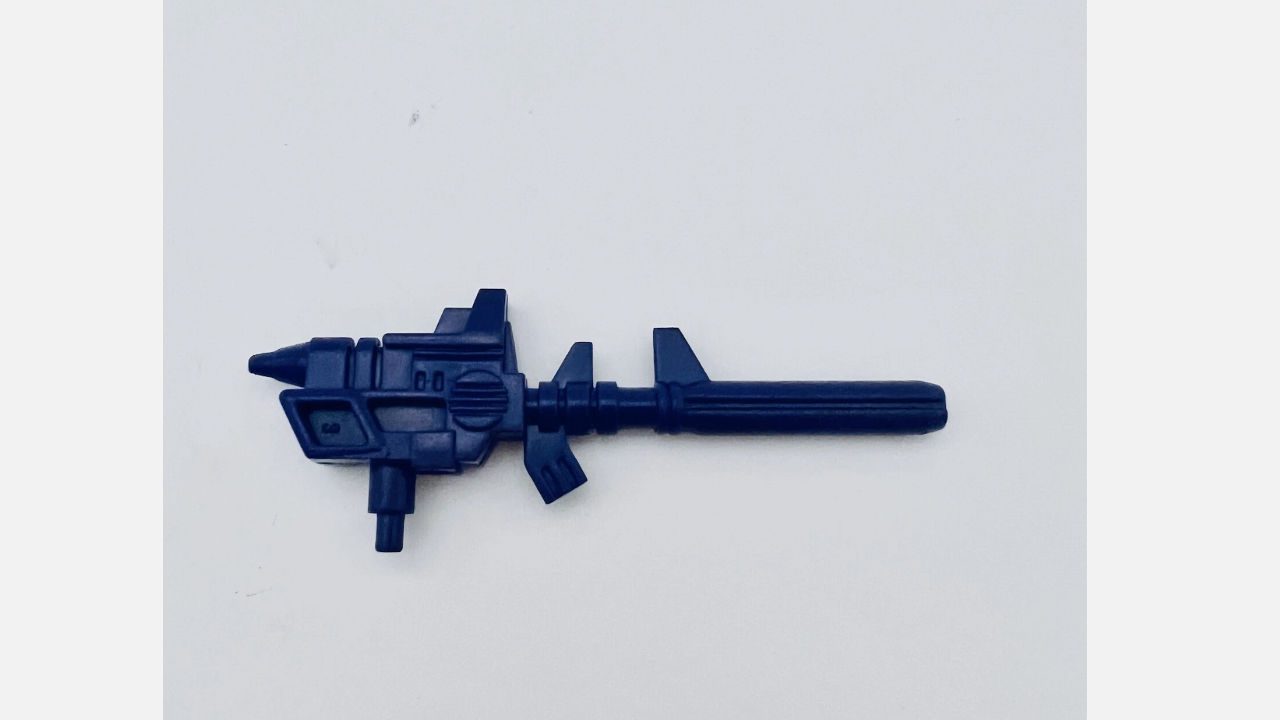 Vintage black Transformers toy gun accessory, plastic, futuristic design, placed on plain white background