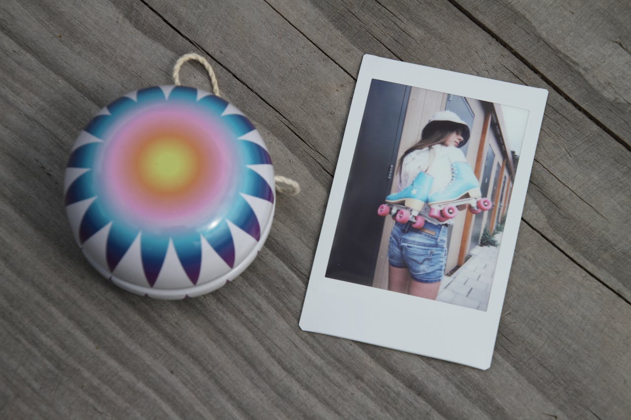 Colorful yo-yo with retro sunburst design beside a Polaroid photo of a girl with roller skates