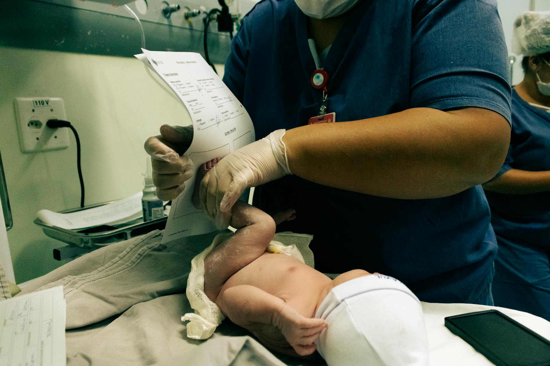 Doctor Holding Newborn Leg over Paper