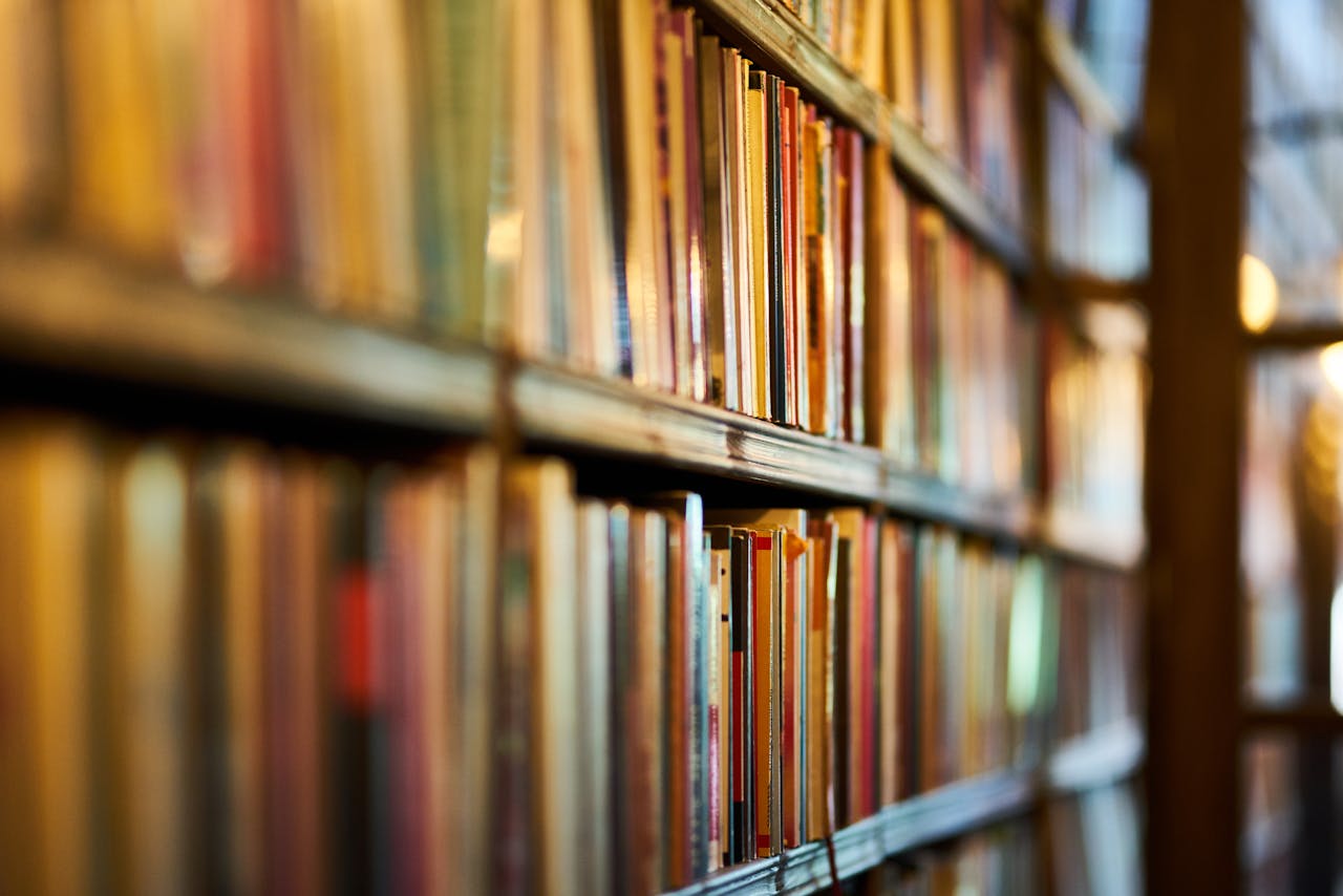Long bookshelf filled with tightly packed colorful books, shot at an angle with a shallow depth of field