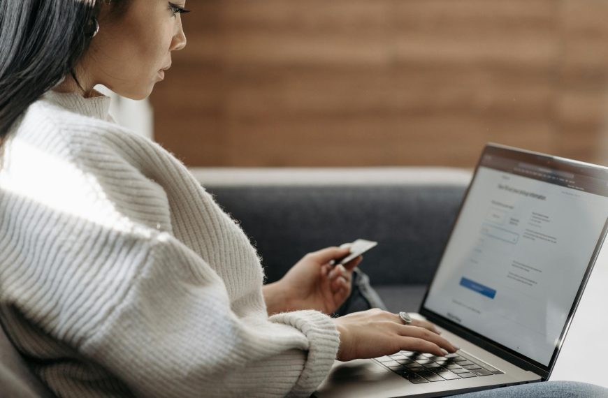 Woman in White Sweater Entering Card Details into Laptop