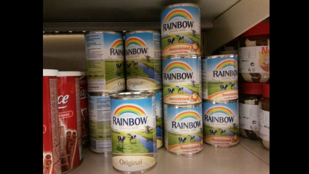 Cans of Rainbow evaporated milk and sweetened condensed milk stacked on a store shelf